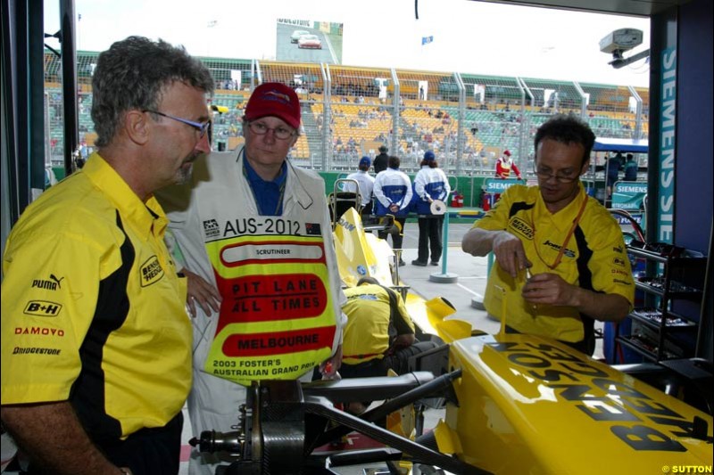 The official race scrutineers oversee the Jordan cars, with team boss Eddie Jordan looking, before they are locked in parc ferme. Australian GP, Melbourne, March 8th 2003.