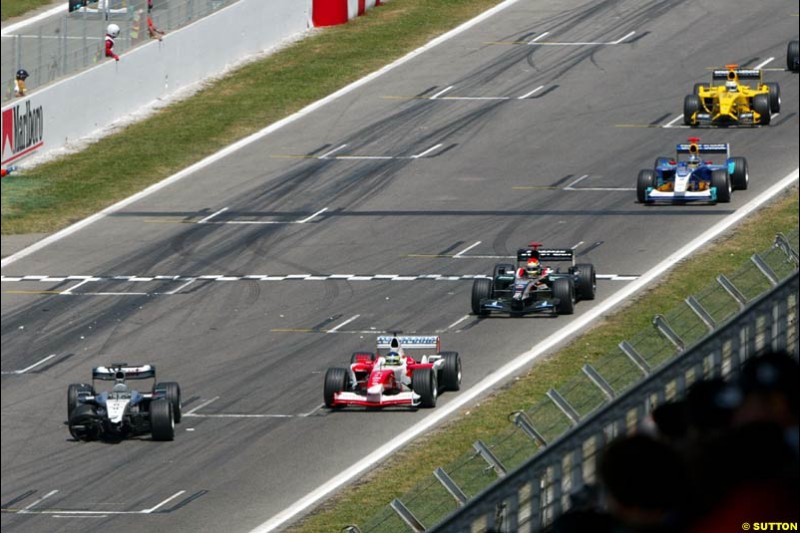 The field streams past the remains of Kimi Raikkonens McLaren. Spanish Grand Prix. Circuit de Catalunya, Barcelona, Spain. May 4th 2003.