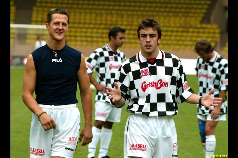 Michael Schumacher chats with Fernando Alonso before a soccer match between the  and quot;Star Team for Children and quot; and Formula One drivers in Monaco May 27, 2003. The event was set up for the benefit of A.M.A.D.E, a charity which helps children all around the world.