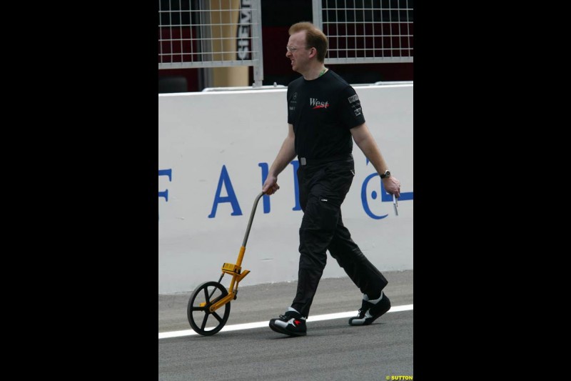 A McLaren mechanic measures the pitlane. Bahrain Grand Prix, Bahrain International Circuit. April 1st, 2004.