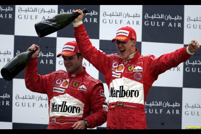 Rubens Barrichello and Michael Schumacher celebrating on the podium. The Bahrain Grand Prix. Bahrain International Circuit, April 4th 2004.