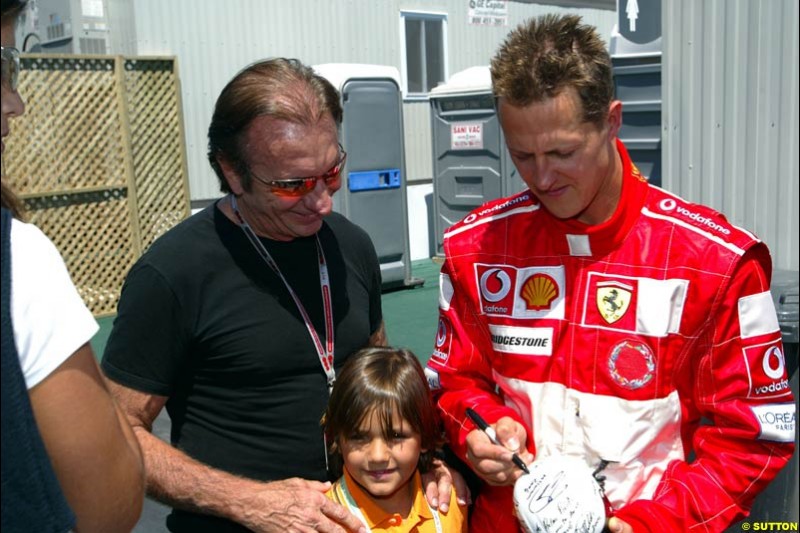 Former World Champion Emerson Fittipaldi gets an autograph for his son from Michael Schumacher, Ferrari, after qualifying. The Canadian Grand Prix, Montreal, Canada. Saturday, June 13th, 2004.