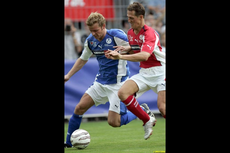 Michael Schumacher challenges ski-jumper Georg Spaeth during a charity soccer match in Mannheim, July 21, 2004.  