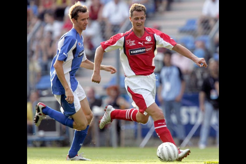 Michael Schumacher challenges German talkmaster Oliver Geissen during a charity soccer match in Mannheim, July 21, 2004.
