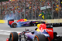 Race winner Sebastian Vettel, Red Bull Racing RB9 celebrates at the end of the race with donuts as Mark Webber, Red Bull Racing RB9 passes, without his helmet