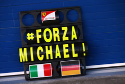 Een Ferrari pitbord met een steunbetuiging aan het adres van Michael Schumacher