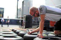 McLaren mechanic marks Pirelli tyres in the pits