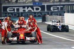 The Ferrari F14-T of Fernando Alonso, Ferrari is recovered back to the pit garage in the second practice session by mechanics as Jenson Button, McLaren MP4-29 passes