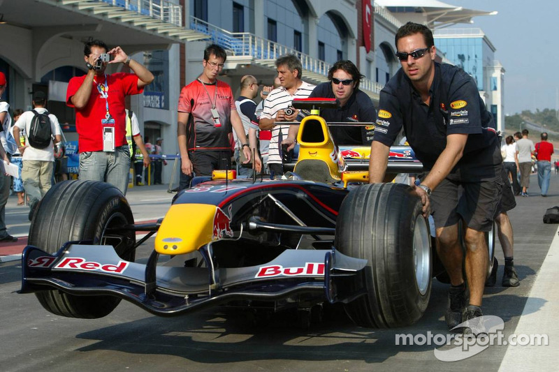 Red Bull Racing team members push car to technical inspection