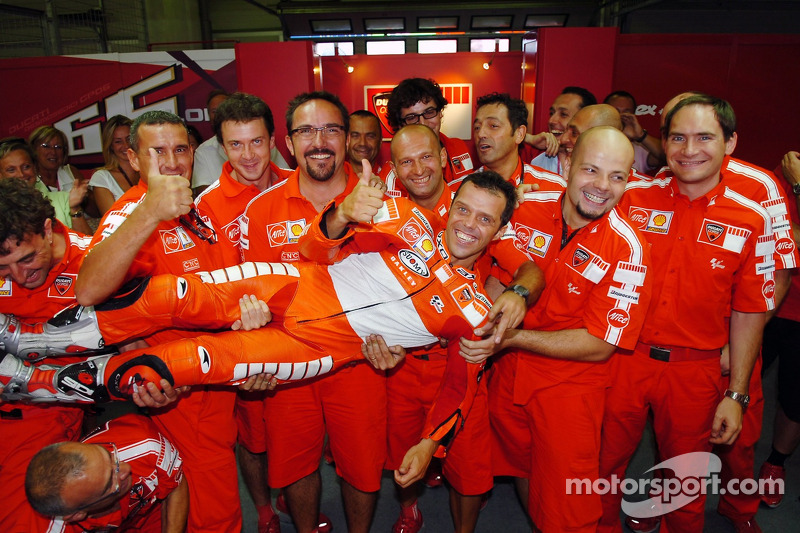 Ganador de la carrera Loris Capirossi celebra con miembros del equipo Ducati