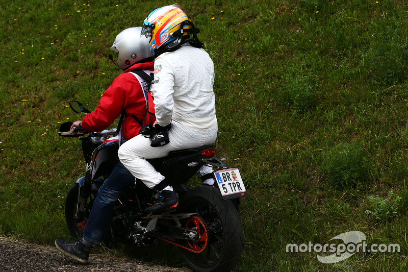 Race retiree Fernando Alonso, McLaren returns to the pits on a motorbike