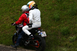Race retiree Fernando Alonso, McLaren returns to the pits on a motorbike