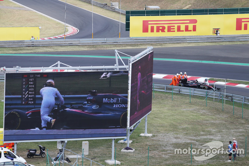 Fernando Alonso, spinge la sue McLaren MP4-30 in pit lane durante le qualifiche