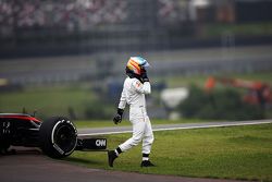 Fernando Alonso si allontana dalla sua McLaren MP4-30 ferma sul circuito nella seconda sessione di p