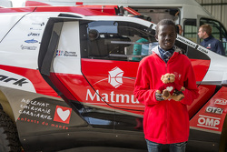 Samba, a Senegalese boy who was saved thanks to Mécénat Chirurgie Cardiaque, with the Peugeot 2008 DKR15+ of Romain Dumas and François Borsotto