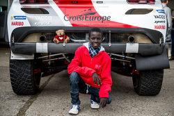 Samba, a Senegalese boy who was saved thanks to Mécénat Chirurgie Cardiaque, with the Peugeot 2008 DKR15+ of Romain Dumas and François Borsotto