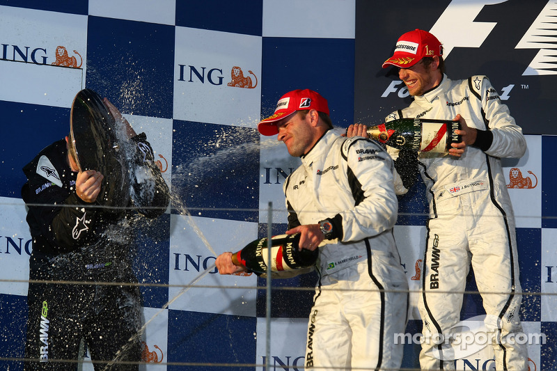 Podium: Ross Brawn uses his trophy to keep himself dry from Rubens Barrichello and Jenson Button