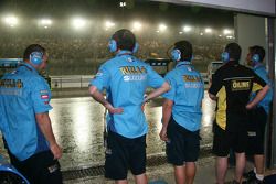 Los miembros del equipo Rizla Suzuki MotoGP se miran una tormenta en el circuito internacional de Lo