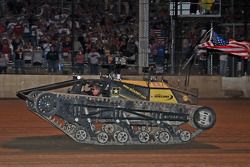 Darrell Waltrip drives a military tank along the front stretch