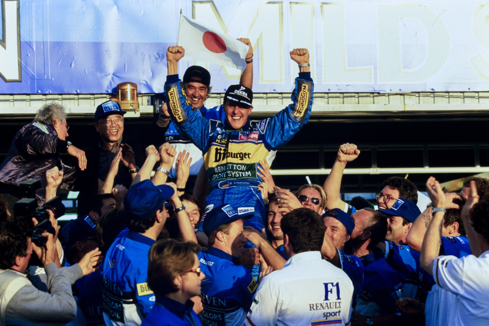 Schumacher and Flavio Briatore celebrate with the Benetton team after clinching the 1995 title in Aida